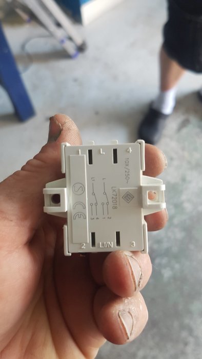 Hand håller en elektrisk installationsmodul med märkningen LK2018.
