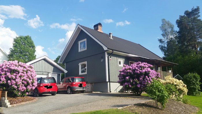 Ett mysigt hus med en veranda och blommande syrenbuskar under en klarblå himmel.