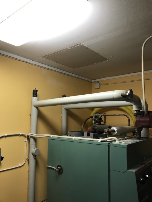 Renoverat innertak med kapad rörinstallation ovanför en pannanordning i ett teknikrum.