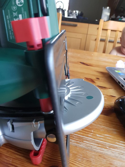 Närbild på en elektrisk verktygsdel med röd plastskruv och höjdjusteringsmekanism.