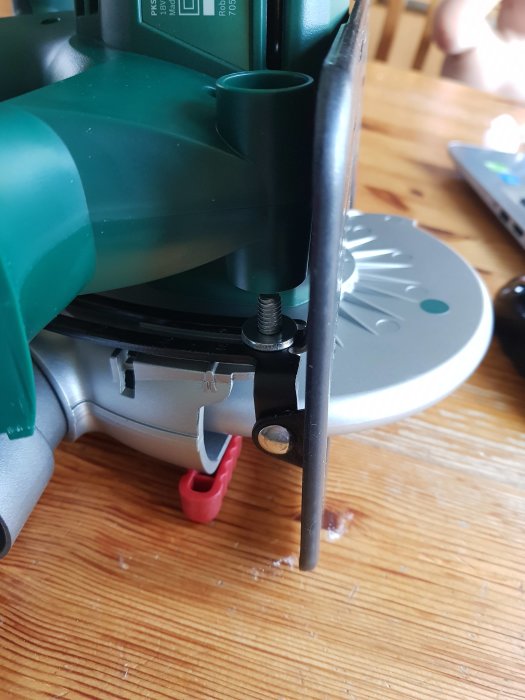 Närbild på en grön och silverfärgad elverktyg med utbytta brickor vid justeringsskruv.