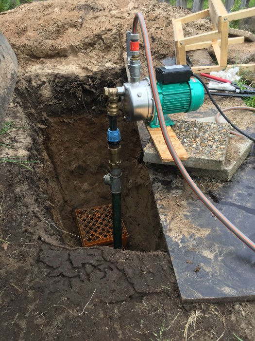 Vattenpump och rörspets installerade i ett öppnat hål i marken för vattenprojekt.