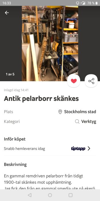 Antik pelarborr i ett överbelamrat förråd, med diverse verktyg och bråte i bakgrunden.