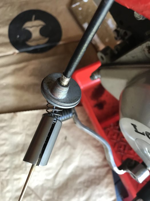 Close-up av ett trottellock på en Loncin 125cc, synlig fjäder och kabel, bakgrund är otydlig.