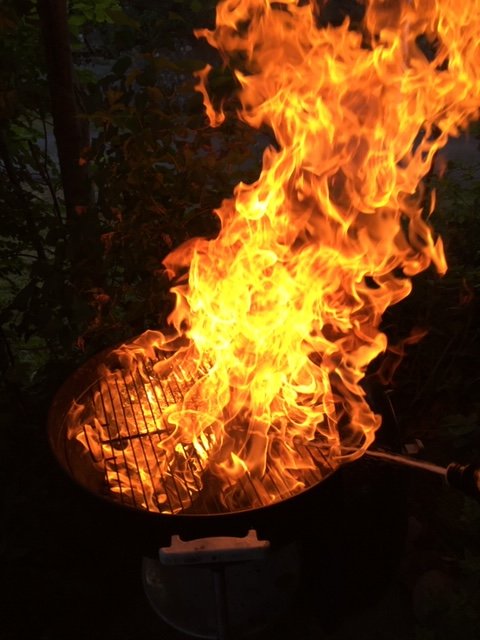 Grill överväldigad av stora eldflammor på kvällen, utan synlig mat eller personer.