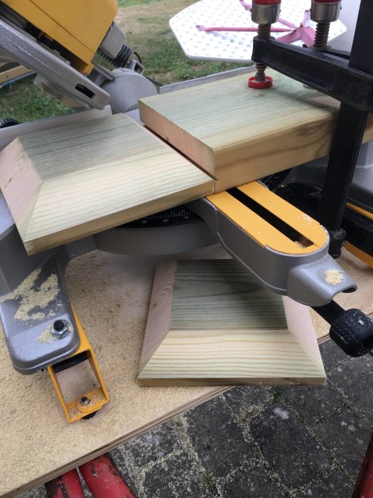 Träbitar kläms fast under kapning med geringssåg för att göra stolphattar.