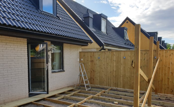 Konstruktion av ny veranda med trästolpar och uppförande av altantak vid en tegelvilla.