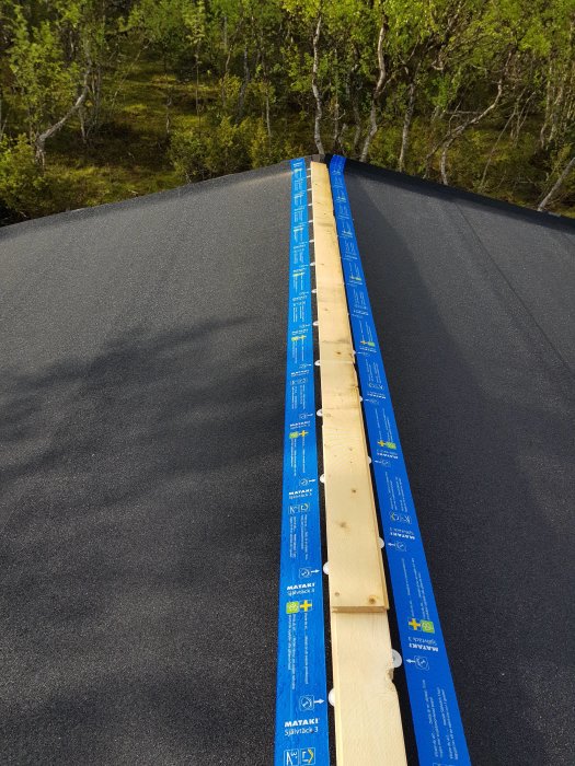 Täckpapp på tak med trälatte längs nocken i behov av en extra remsa för att slutföra täckningen.