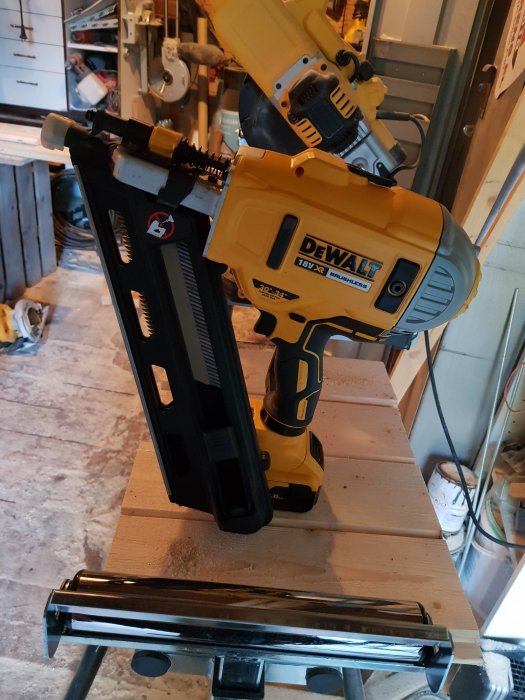 Gult och svart batteridrivet spikpistol från DeWalt står på ett träbord, redo för panelarbete.