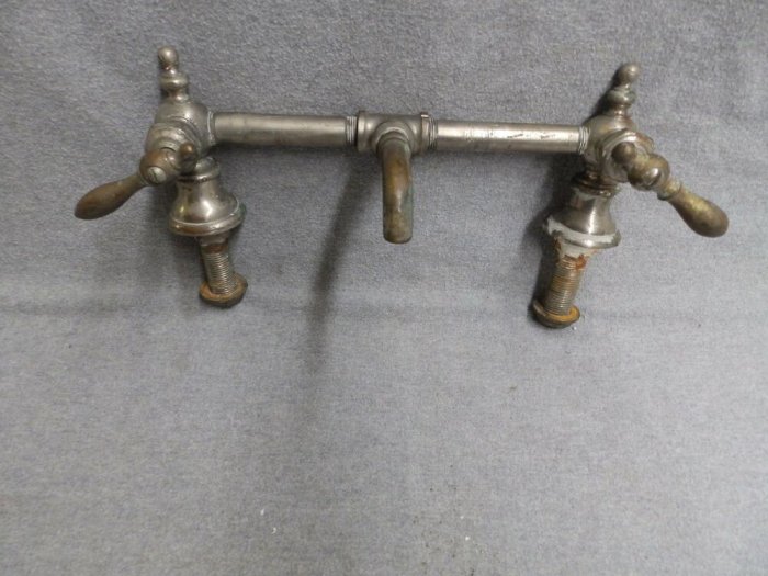 Gammaldags bridge faucet i silverfärg med två vred och central pip, påminner om tidigt 1900-tals design.