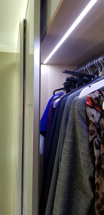 Walk-in closet med LED-belysning och hängande kläder, omvandlat från ett barnrum.