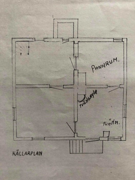 Handritad planritning av ett källarplan i ett hus med märkta rum som "Pannrum" och tydliga vägglinjer.