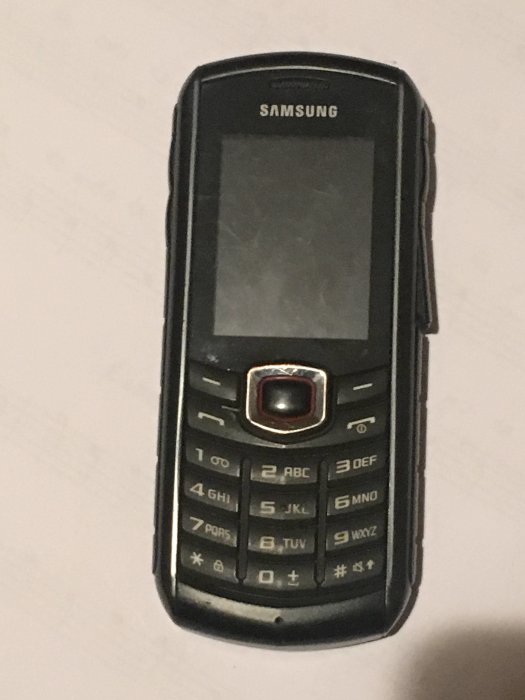 Samsung B2710 knapptelefon, svart med synliga knappar och skärm, robust och vattentålig design.