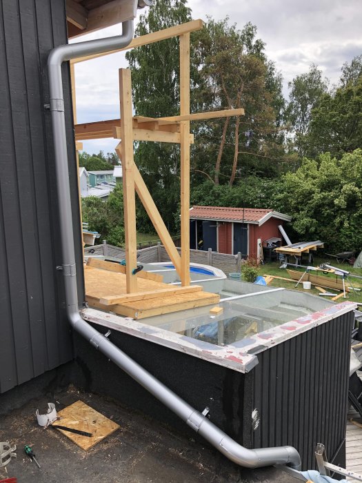 Stuprör och krökar installerade på hus för att förhindra överspolning, omgiven av byggmaterial.