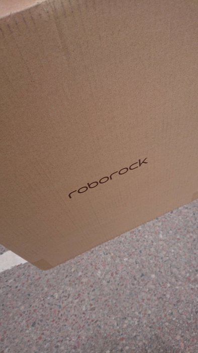 Roborock kartong på ett grått granitgolv som symboliserar en ny robotdammsugare.