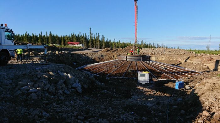 Arbetsplats med armeringsjärn och gjutning av betongfundament i skogsmiljö.