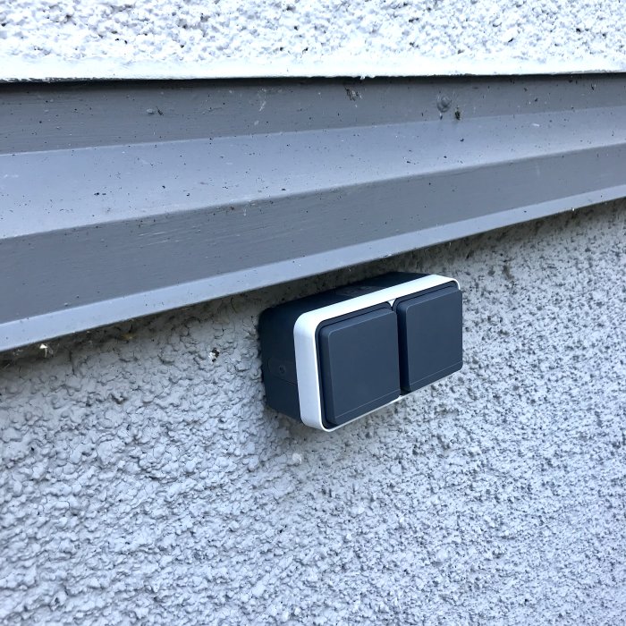 Nyinstallerad, modern grå dubbelsensor på en riven yttervägg under vit fönsterfoder.