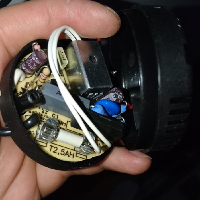 Närbild på insidan av en öppen lampdimmare med kablar och elektroniska komponenter.