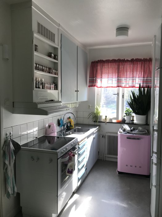 Ljust retrokök med öppna hyllor, rosa Smeg-retro-diskmaskin och vit spis.