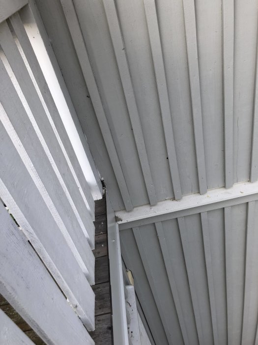 Hål i fasaden ovanför balkongänden där trä och isolering syns.
