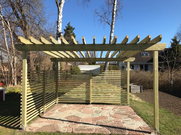 En nybyggd träpergola med ribbade sidoväggar i en trädgård med soligt väder.