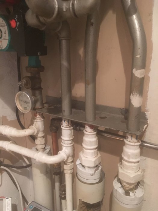 Gammal fjärrvärmecentral med övermålade rörkopplingar i ett radhus från 70-talet.