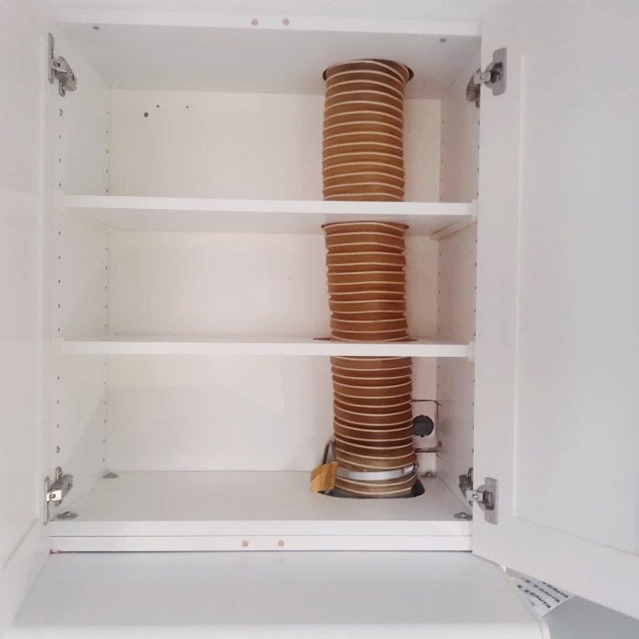 Gammal, rund köksfläkt i vitt skåp som förbereds för byte inför köksrenovering.