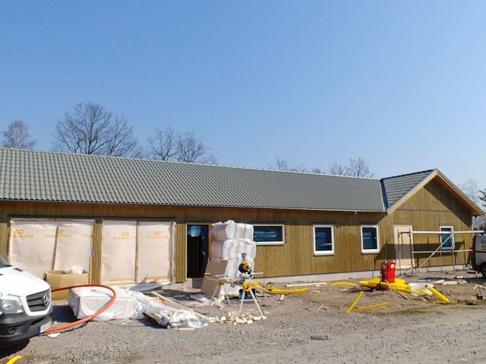 Ett hus under renovering med oskyddade isoleringsskivor och träreglar synliga på väggytor externt.