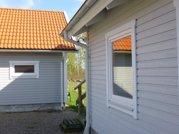Exteriör av hus med 120 mm liggande träpanel och ett fönster med vita karmar.