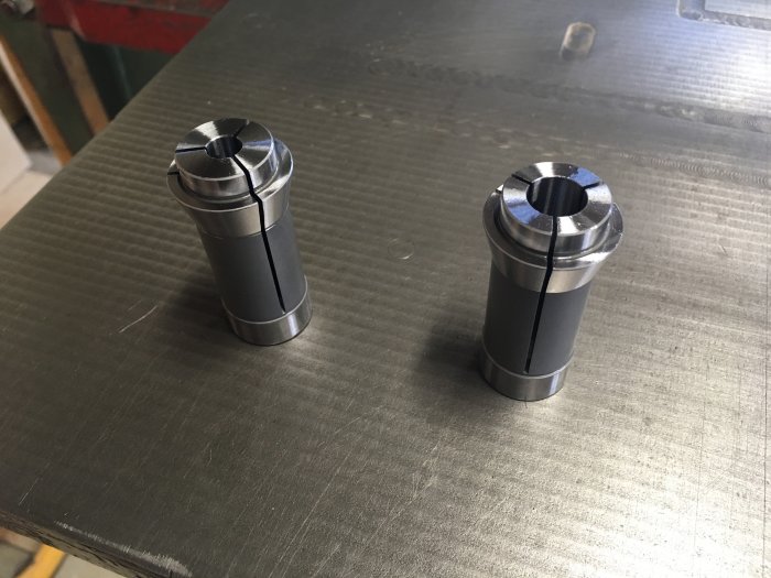 Två metalliska spännhylsor, en 12 mm och en 8 mm, på en verkstadsbänk i metall.
