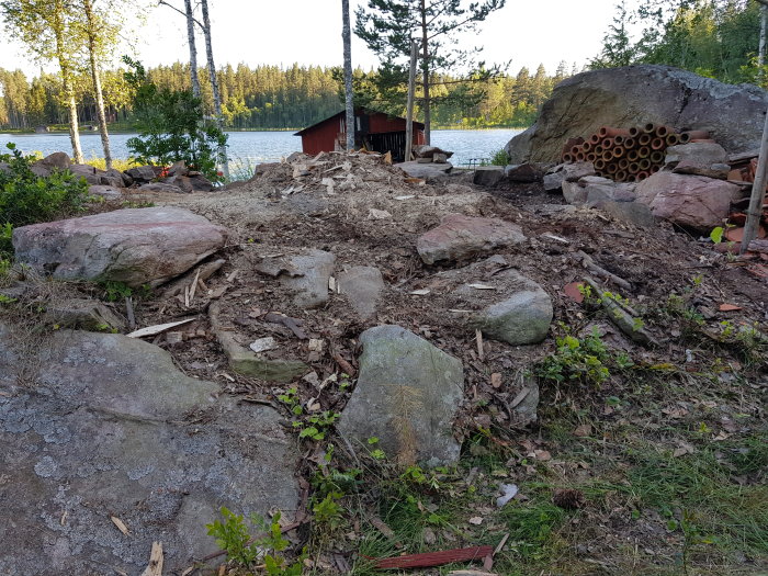 Område med stenar och skräp vid sjö, förberedelse för gjutning av grund.