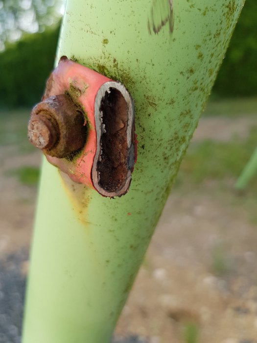 Skadad gungställningsstolpe med rostig bult och utskuren del.