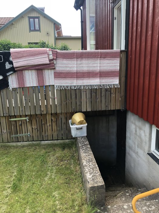 Fuktig källartrappa med skugga och början till röta vid dörrkarmen på ett tvåvåningshus.