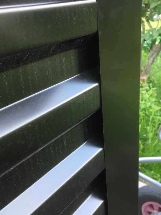 Korrugerad plåt med liggande profil möter en vertikal vinkelplåt på ett skjul.
