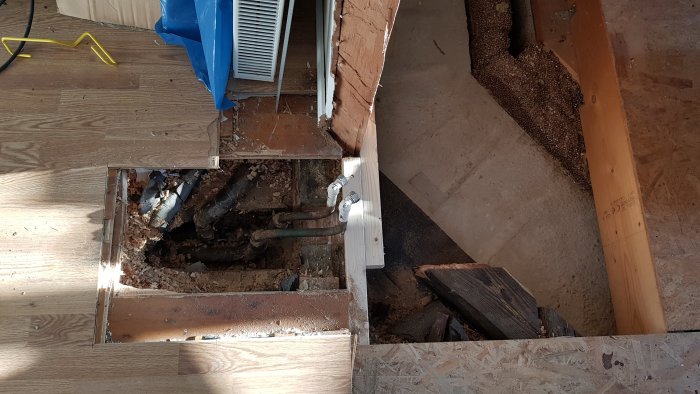 Golv med öppning där radiatorrör syns, redo för förlängning i en renovering.