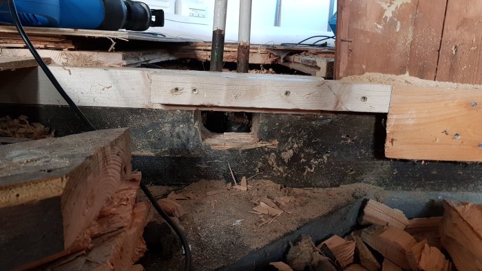 Upprivna golvet med exponerade golvbjälkar och synliga radiatorrör som ska förlängas i ett utbyggnadsprojekt.