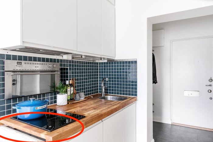 Sned bänkskiva i kök med externa kablar, induktionshäll och blå kakelvägg.