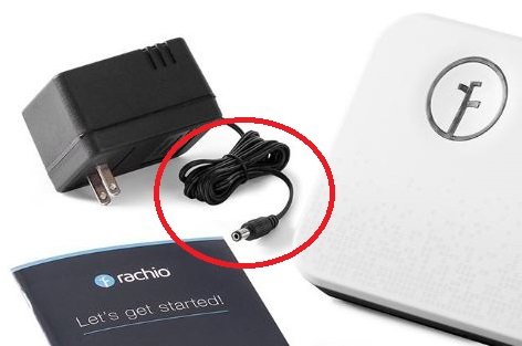 Bevattningscontroller med strömadapter, vars anslutning är markerad, samt en instruktionsbok.