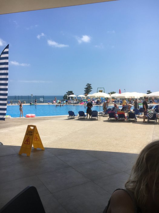 Utsikt över en solig pool vid ett familjehotell i Sunny Beach med folk som badar och solar.