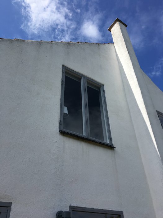 Nytt träfönster monterat i putsad fasad på ett lättbetongshus utan synliga droppbleck under en klarblå himmel.