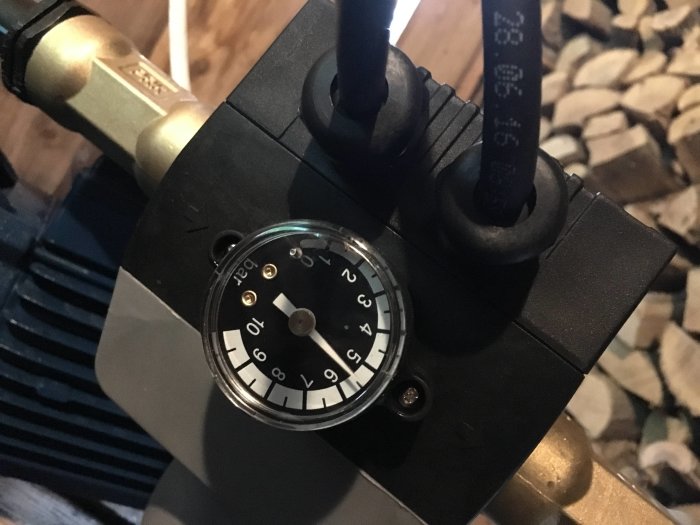 Närbild på en pump med monterad tryckmätare som visar 5 bar i en trädgårdsbevattningssystem.