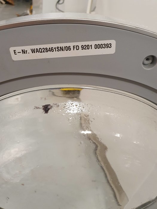 Närgräns på etikett av en Bosch Avantixx 7 med serienummer över en del av en tvättmaskintrommel.