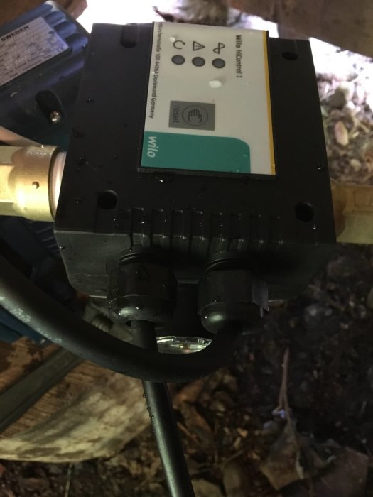 Pump med kablar anslutna och informationsetikett, indikerar möjlig elektrisk anslutningsfråga.