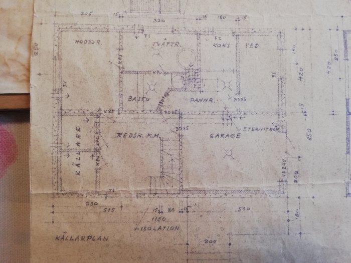 Gammal arkitektritning av källarplan med markerade utrymmen för garage, bastu, pannrum, och hobbyrum.