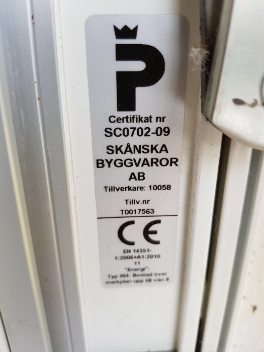 Certifikat- och prestandainformation på vit fönsterkarm med svart text och CE-märkning.