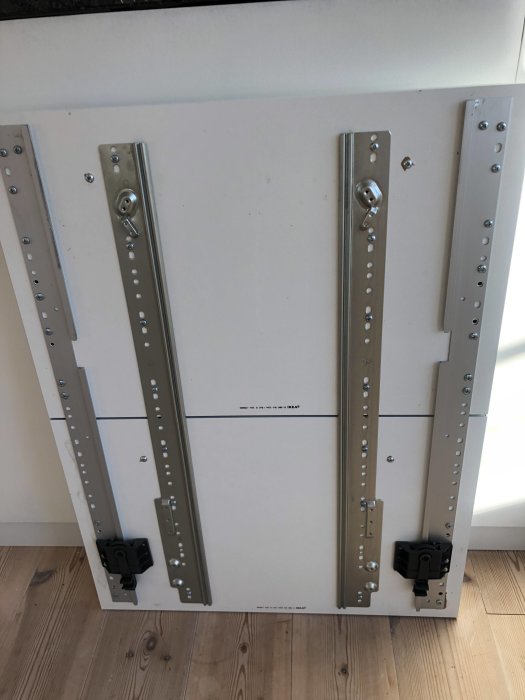 Luckan på en äldre Ikea Lagan diskmaskin med två metallglidhållare och en lös hängande lucka på grund av trasig plasthållare.