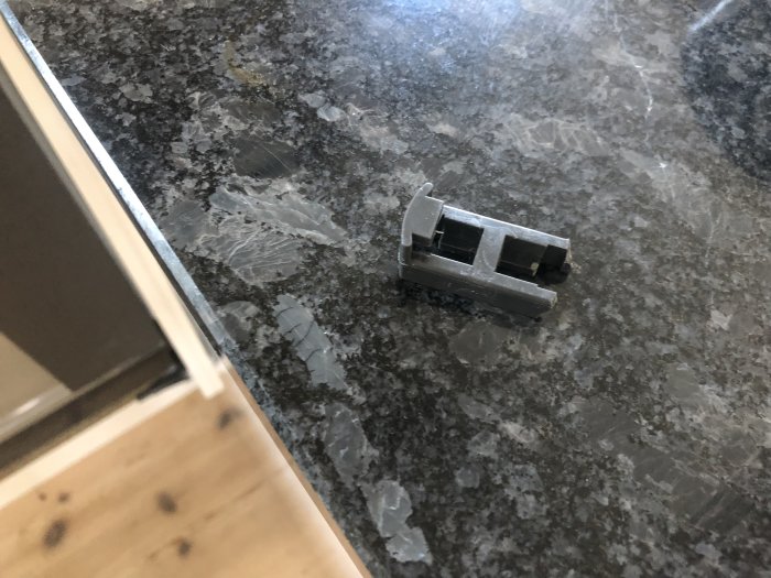 Söndrig plastglidhållare från Ikea Lagan diskmaskin på marmorbänkskiva.