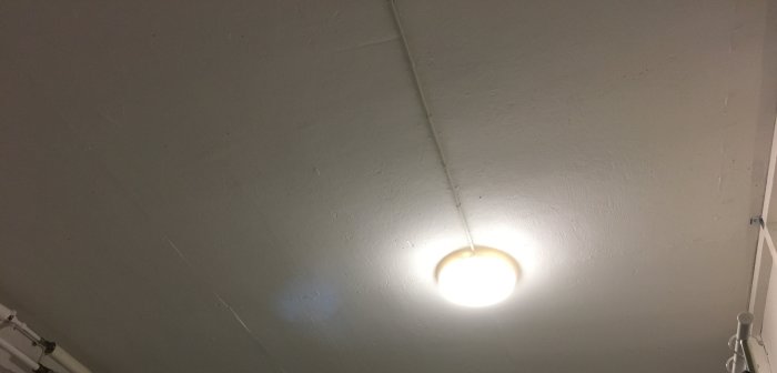Plafond med tänd lampa i källartak som ger otillräckligt ljus för rummet.