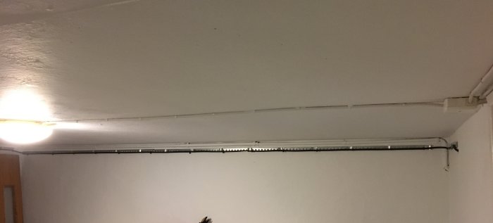 En källarbelysningsinstallation med en plafond och synlig elektrisk kabeldragning längs taket.