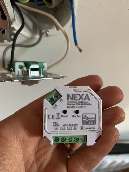 Nexa Dosdimmer ZV-9101 hålls framför elinstallation, med synliga ledningar och dosa i bakgrunden.